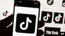 ARCHIVO - El logotipo de TikTok se muestra en un teléfono móvil frente a la pantalla de una computadora, el 14 de octubre de 2022, en Boston.