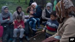 Stranded in the northern Greek border station of Idomeni for 15 days, Syrian refugees sit next to a fire as they wait to be allowed to cross to Macedonia, March 5, 2016.
