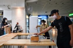 A man receives a coffee in a cart pulled by a rope as a transportation system after a cafe adopted a social distance policy for their customers amid fears of coronavirus outbreak in Bangkok, Thailand, March 20, 2020.