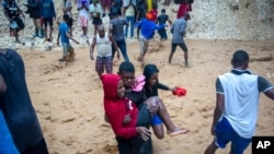 A man carries a woman across the Tet Dlo river during the passing of Tropical Storm Laura in Port-au-Prince, Haiti, Aug. 23, 2020. 