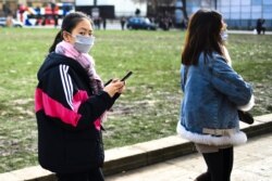 Two women in masks walk in Parliament Square, in London, Feb. 1, 2020.
