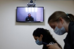 Russian opposition leader Alexei Navalny is seen on a screen via a video link during a hearing at the Petushki district court in Petushki, May 26, 2021.