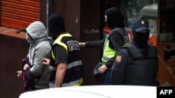 Spanish police arrest a man, left, accused of collaborating with the Islamic State, after searching a cybercafe in Mataro near to Barcelona, Dec. 8, 2015.