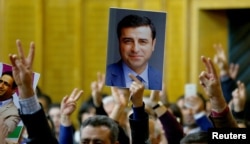 FILE - A supporter holds a portrait of Selahattin Demirtas, detained leader of Turkey's pro-Kurdish opposition Peoples' Democratic Party at a meeting at the Turkish parliament in Ankara, Nov. 8, 2016.
