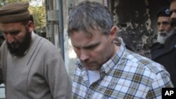 A U.S. consulate employee involved in a shootout that killed two Pakistani men is escorted by police after facing a judge in Lahore, January 28, 2011.