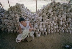 FILE - A man cleans a skull near a mass grave at the Chaung Ek torture camp run by the Khmer Rouge in this undated photo.