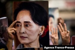 Seorang pengunjuk rasa memegang foto pemimpin sipil Myanmar yang ditahan Aung San Suu Kyi selama demonstrasi menentang kudeta militer di luar Kedutaan Besar Myanmar di Bangkok pada 7 Februari 2021. (Foto: AFP)