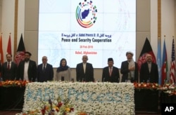 FILE - Afghan President Ashraf Ghani, center, and delegates stand for the national anthem during the second Kabul Process conference at the Presidential Palace in Kabul, Feb. 28, 2018.