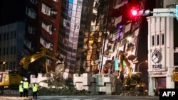 台湾花莲，救援人员站在一栋严重倾斜的大楼前。(2024年4月3日)