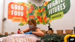Volunteers pack boxes of food for distribution, at The Capital Area Food Bank, in Washington, Oct. 5, 2021. 
