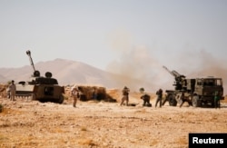 FILE - Hezbollah fighters stand near military tanks in Western Qalamoun, Syria, Aug. 23, 2017.