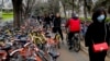 Residents ride bicycles from bike-sharing company Ofo try to pedal through a sidewalk crowded with bicycles from the bike-sharing companies Ofo, Mobike and Bluegogo, near a bus stand in Beijing, China, March 23, 2017. As many as 2.2 million of these two-wheelers have been deployed, which are available for rent for as little as U.S. 7 cents for half an hour, in the latest symbol of heavy spending in China&#39;s internet sector where startups are in a race to attract more users to their services.