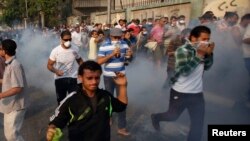 Demonstran anti pemerintah berlarian di jalanan Kornish El Nile, dekat Lapangan Tahrir di Kairo setelah polisi Mesir menembakkan gas air mata (6/10). 