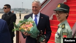 U.S. Defense Secretary Jim Mattis receives a bouquet upon arrival at an airport in Beijing, China, June 26, 2018.