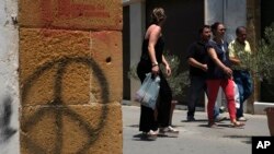 People cross the Ledra street crossing point that leads from the north to the south between the U.N buffer zone in the divided capital Nicosia, Cyprus, June 28, 2017. 
