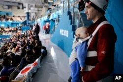 Jeff Whitmore from Wisconsin watches as his 1-year-old son, Escher, sleeps during the women's curling match at the 2018 Winter Olympics in Gangneung, South Korea, Feb. 17, 2018.