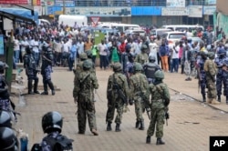 Ugandan army soldiers stand in front of a crowd during protests by supporters of Ugandan pop star-turned-lawmaker Bobi Wine, whose real name is Kyagulanyi Ssentamu, in Kampala, Uganda, Aug. 31, 2018.