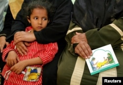 FILE - A woman holds a card in her lap about the problems with FGM during a session to educate women in Minia, Egypt, June 2006.