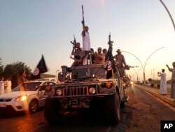 FILE - Fighters from the Islamic State group parade in a commandeered Iraqi security forces armored vehicle on the main road at the northern city of Mosul, Iraq, June 23, 2014.