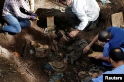 Members of the forensic team and auxiliary workers work at an exhumation site in the village of La Joya as they search for human remains of the EL Mozote massacre in the town of Meanguera, El Salvador, Nov. 24, 2016.