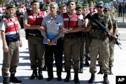 FILE - Paramilitary police and members of the special forces escort people suspected of involvements in a failed 2016 coup attempt, outside the courthouse at the start of a trial, in Ankara, Turkey, Aug. 1, 2017.