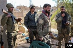 Fighters with the U.S.-backed Syrian Democratic Forces (SDF) check a makeshift camp for Islamic State (IS) group members and their families in the town of Baghuz, eastern Syria, March 9, 2019.