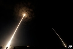 FILE - During a time exposure the Falcon 9 SpaceX rocket is seen, left, as it lifts off from launch complex 40 at the Cape Canaveral Air Force Station in Cape Canaveral, Fla., July 18, 2016.
