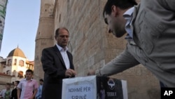 FILE - Kosovo Muslims donate money in a box labeled "Help for Syria" in front of the Grand Mosque in Kosovo's capital Pristina in this 2012.