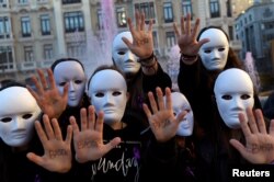 Students wearing masks pose with the word "Enough" written on their hands during a performance to commemorate victims of gender violence, during the U.N. International Day for the Elimination of Violence against Women, in Oviedo, Spain Nov. 25, 2016.