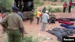 Kenyan military personnel and Red Cross volunteers carry bodies of people killed at a quarry in a village in Korome, outside the border town of Mandera, Dec. 2, 2014.