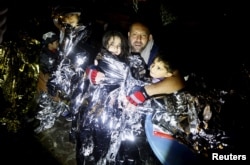A Syrian refugee tries to keep his children warm after being rescued by Greek fishermen on the Greek island of Lesbos Oct. 19, 2015.