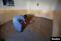 FILE - A farmer inspects his wheat stocks in Basheeqa, Iraq, Feb. 8, 2017.