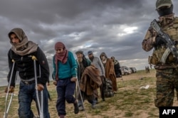 Men suspected of being Islamic State fighters wait to be searched by members of the Kurdish-led Syrian Democratic Forces (SDF) after leaving the IS group's last holdout of Baghuz, in Syria's northern Deir Ezzor province, Feb. 27, 2019.