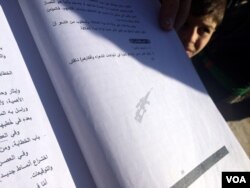 Teachers point out AK-47 logos and prayers for dead al-Qaida leaders on book pages in Mosul, Iraq, Nov. 23, 2016. (H. Murdock/VOA)