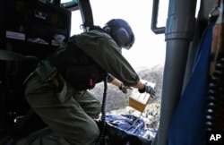 This U.S. Coast Guard image shows Petty Officer 2nd Class Kenneth Krowel dropping a box of MRE's to stranded residents near Utuado, Puerto Rico, Oct. 3, 2017. Nearly two weeks after the storm, 95 percent of electricity customers remain without power.