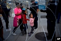Pedestrians pass barbed wire at a legal Mexico-U.S. border crossing where U.S. officials check the identifications of people entering the U.S. from Tijuana, Mexico, Monday, Nov. 19, 2018.