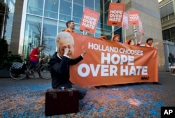 A man poses as crying firebrand anti-Islam lawmaker Geert Wilders during a small demonstration outside parliament, rear, in The Hague, Netherlands, March 16, 2017.