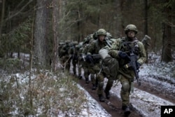 FILE - Lithuanian troops practice during a NATO military exercise, 'Iron Sword,' at the Rukla military base some 130 km. (80 miles) west of the capital Vilnius, Lithuania, on Nov. 28, 2016.