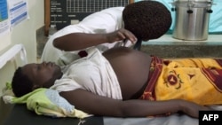 FILE - A health care worker attends to a pregnant woman in Busiu, in Mbale district, eastern Uganda, Sept, 27, 2011.