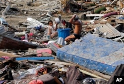 Residents take a bath amid remains of toppled homes and structures at the earthquake and tsunami-hit Palu, Central Sulawesi, Indonesia, Oct. 5, 2018.