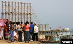 A group of Sri Lankan visitors at the new deep water shipping port watch a Chinese dredging ships work in Hambantota, March 24, 2010.