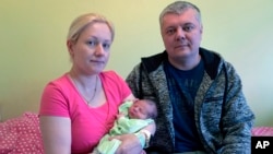 In this photo taken on Friday, Nov. 16 2018 in Tallinn, Estonia, parents Andrejs and Olga Lunde hold their three-day old son Oskar, a few minutes after officially registering his name online. (AP Photo/David Keyton)