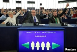 FILE - Members of the European Parliament vote in favor of the Paris climate change agreement during a voting session in Strasbourg, Oct. 4, 2016.