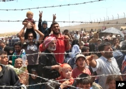 Syrian refugees, flee intense fighting in northern Syria between Kurdish fighters and Islamic State militants, are seen massed at the Turkish border in Akcakale, southeastern Turkey, June 15, 2015.