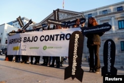 People hold placards reading "Decisions that kill" during a gathering to demand a halt of arm sales to Saudi Arabia outside Parliament in Madrid, Oct. 24, 2018.