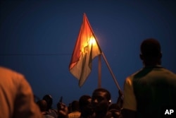 A protester holds a Burkina Faso national flag during a protest against a recent coup in Ouagadougou, Burkina Faso, Sept. 21, 2015.