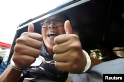 Detained Reuters journalist Wa Lone gestures to the media as he is escorted by police after a court hearing in Yangon, Myanmar, Apr. 11, 2018.