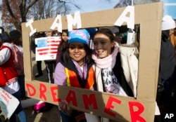Demonstrators Karina Velasco, left, and Gabi Sanchez hold a sign during an immigration rally in support of the Deferred Action for Childhood Arrivals (DACA), and Temporary Protected Status (TPS), programs, on Capitol Hill in Washington, Dec. 6, 2017.