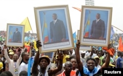 FILE - Supporters of Congolese President Joseph Kabila carry his photographs during a pro-government rally in the Democratic Republic of Congo's capital Kinshasa, July 29, 2016.