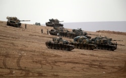 FILE - Turkish soldiers hold their positions with their tanks on a hilltop on the outskirts of Suruc, at the Turkey-Syria border, overlooking Kobani, Syria, during fighting between Syrian Kurds and Islamic State militants, Oct. 12, 2014.